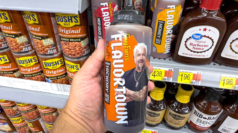 person holding a bottle of flavortown hickey bbq sauce in the store
