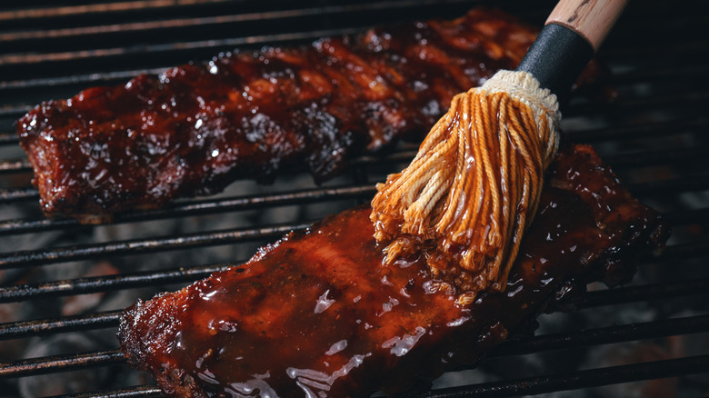 brushing bbq sauce on grilled ribs