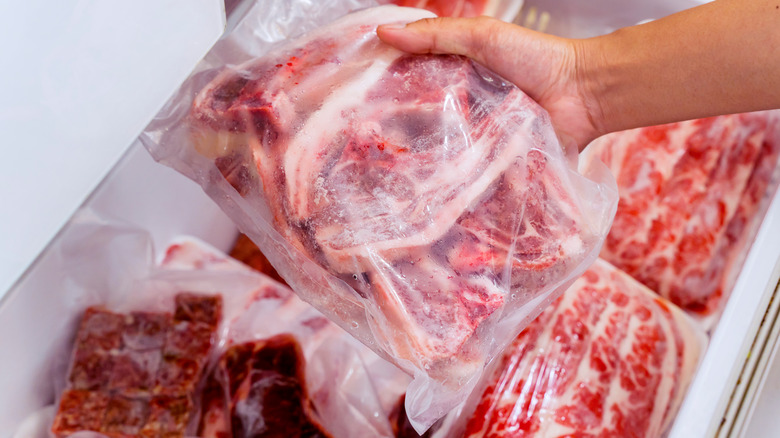 Hand pulling frozen steaks from freezer