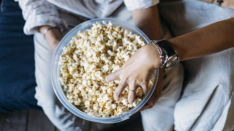 Hand digging into bowl of popcorn