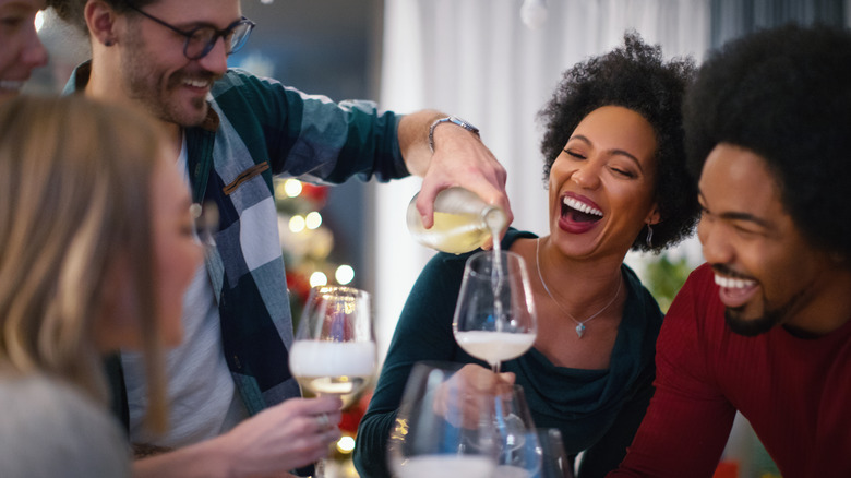 Group of people pouring wine at dinner party