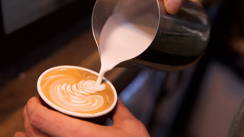 Adding steamed milk to coffee