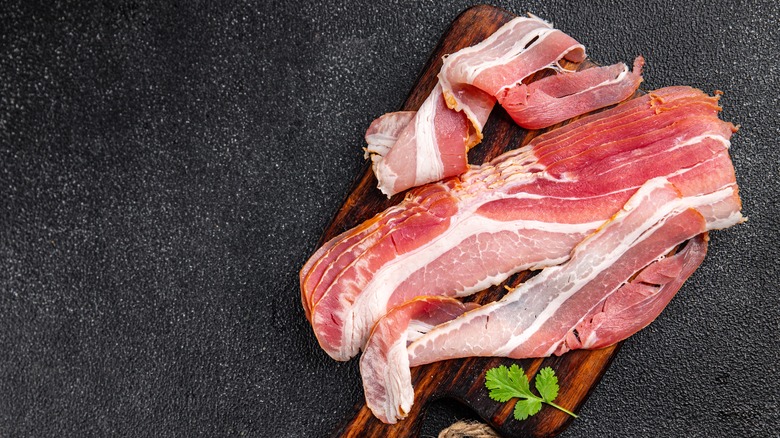 raw bacon slices on cuttingboard