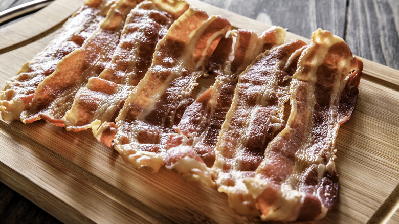 cooked bacon slices on wooden board