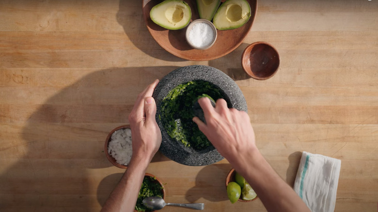 Grinding onions, cilantro, chilies, and lime in molcajete