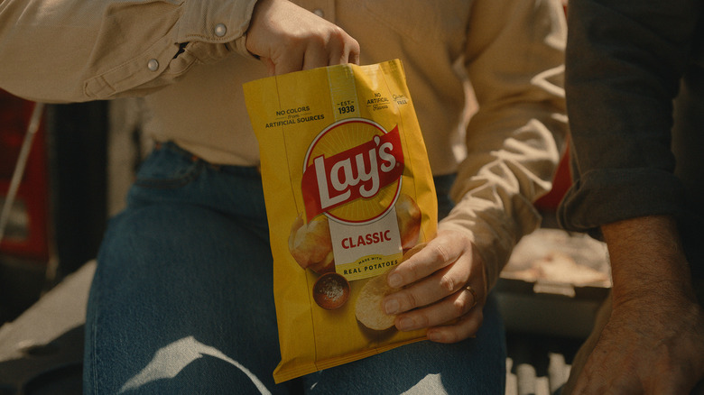 Someone reaching into a bag of lays