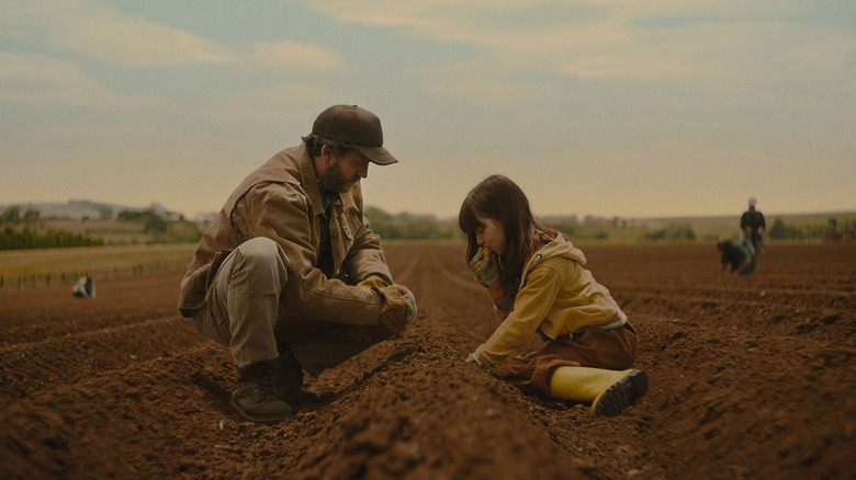 Father and daughter sitting in the dirt on a potato farm
