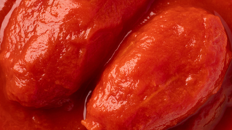Two canned tomatoes sit in their own juices