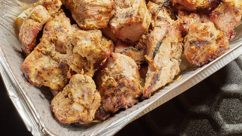 Pieces of grilled chicken in a foil container