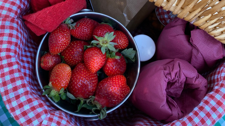 Close-up inside a picnic basket with strawberries and wrapped wine glasses