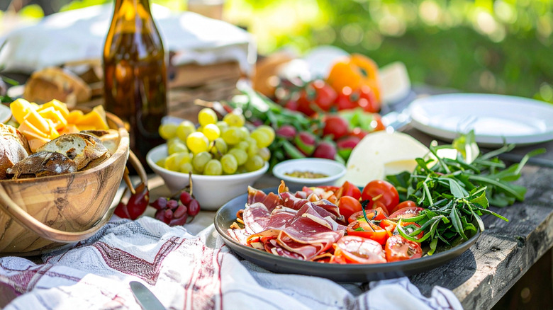 A selection of meat, tomatoes, and arugula sit on a plate