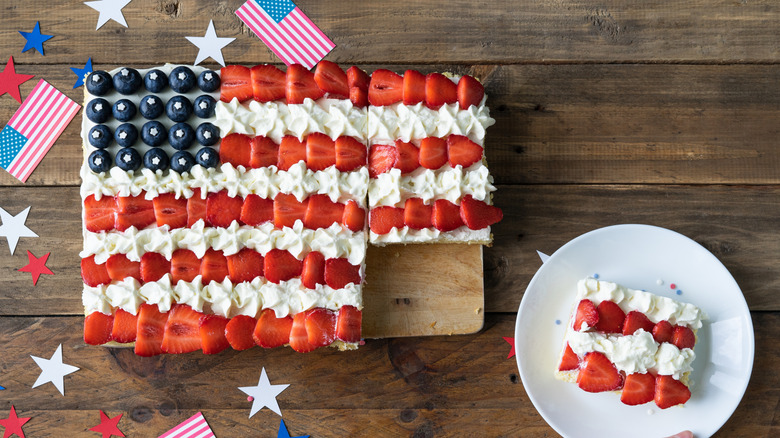 A flag cake with fruit and and whipped cream.