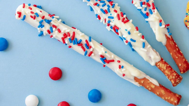 Pretzel rods covered in white chocolate and sprinkles.