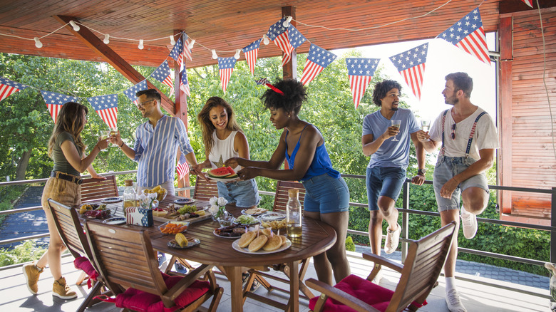 Friends gathering around a table set with food on July 4.