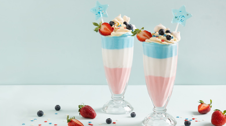 Two patriotic milkshakes topped with fruit.