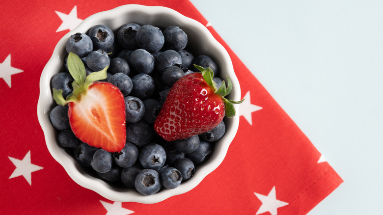 A bowl of blueberries, topped with strawberry halves.