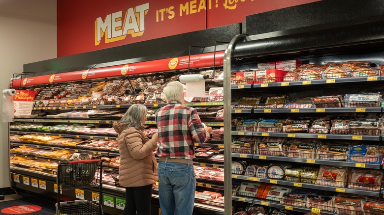 A couple shops the meat selection of a Grocery Outlet