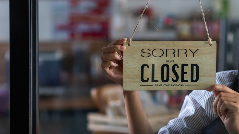 Employee hanging wooden closed sign in window