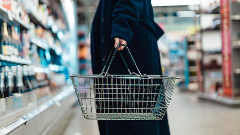 Empty basket in a woman's hand standing in a supermarket