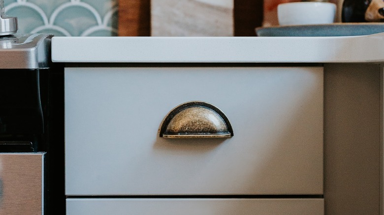 Aged brass drawer pull on white cabinet