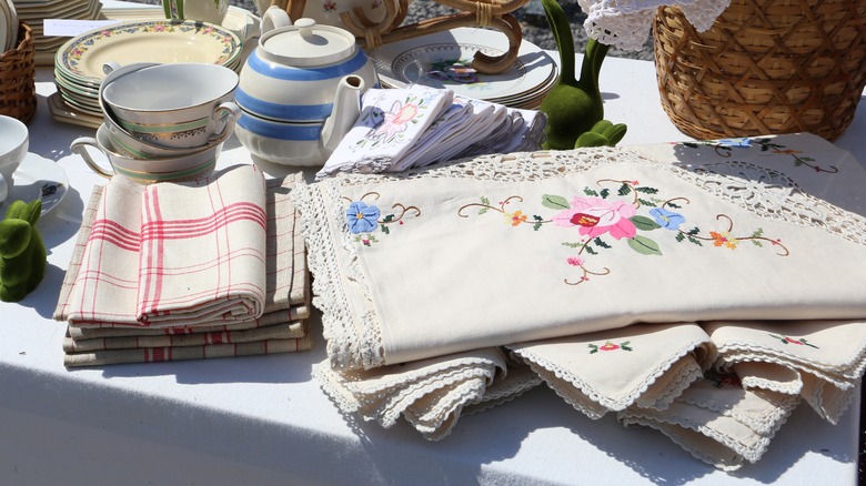 Vintage linens laid next to dishes at a flea market