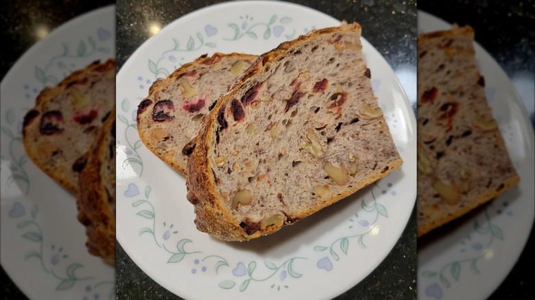 Two slices of Kirkland Signature Cranberry Walnut Round Bread sit on a plate.
