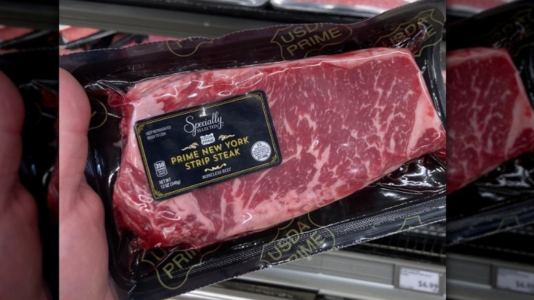 A person holds a steak in the Aldi meat department