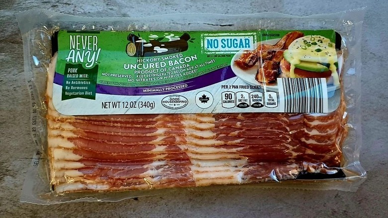 A package of Aldi's Never Any Hickory Smoked Uncured Bacon sits on a stone surface