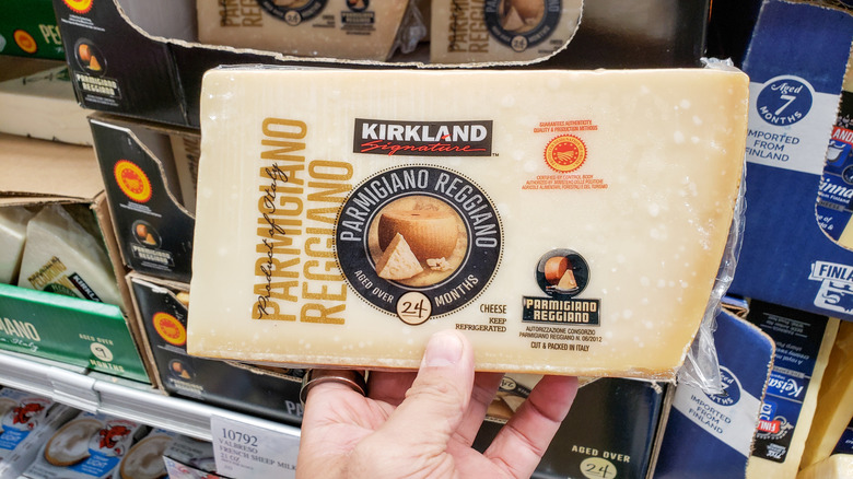 hand holding up a wedge of kirkland parmigiano-reggiano at Costco