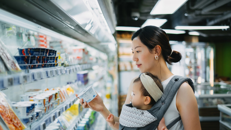 A woman shopping for organic yogurt in a grocery store aisle