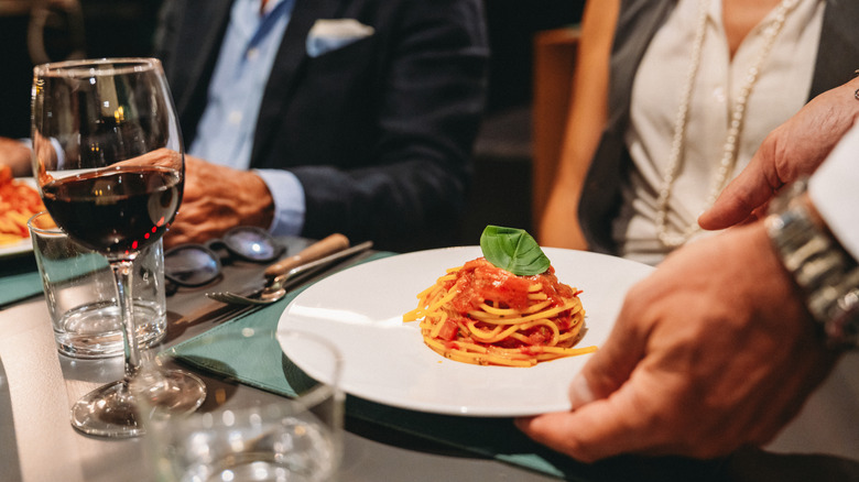 Server placing pasta dish on table