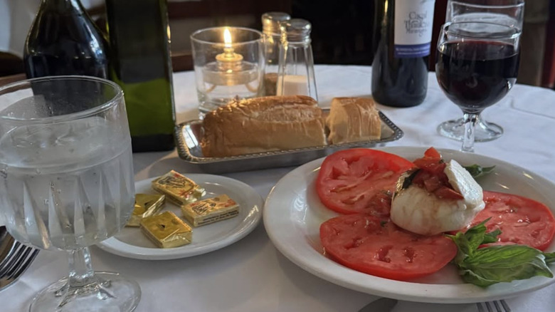 Burrata sits on a table with bread and wine.