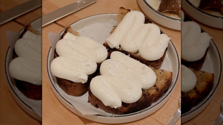 Toast with ricotta is served on a shallow plate.