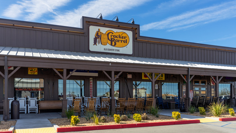 The exterior of a Cracker Barrel restaurant with rocking chairs in long rows