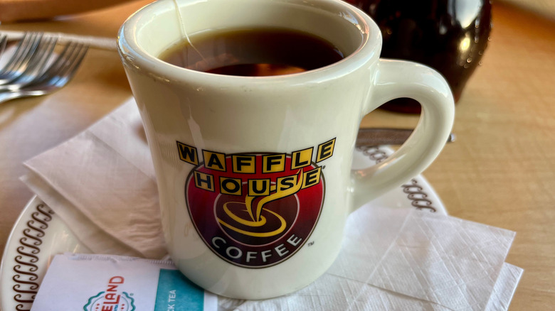 Closeup of a Waffle House coffee mug on a saucer with napkins and sugar packets