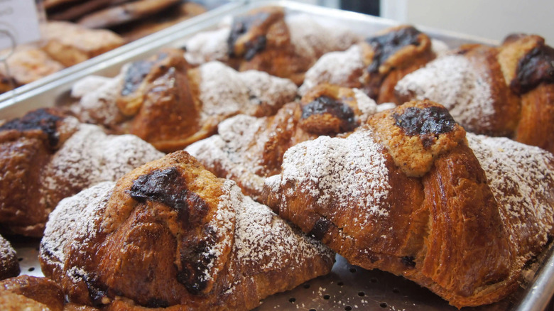 A tray of Arsicault's laminated croissants, dusted with powdered sugar and sitting on a baking tray