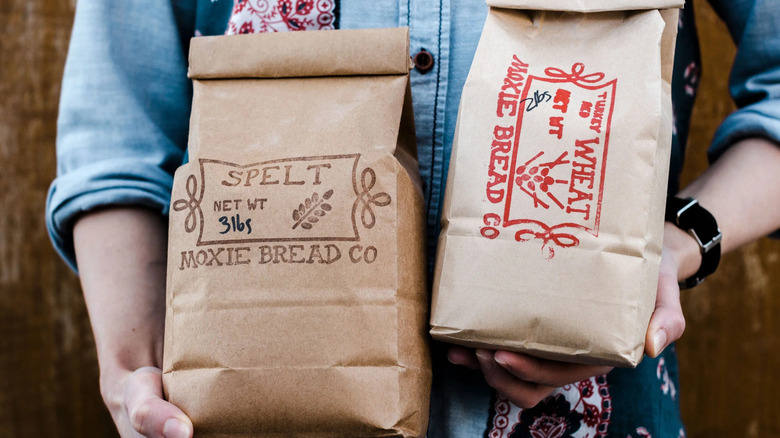 A baker holding two bags of Moxie Bread Company's in-hous-milled flour