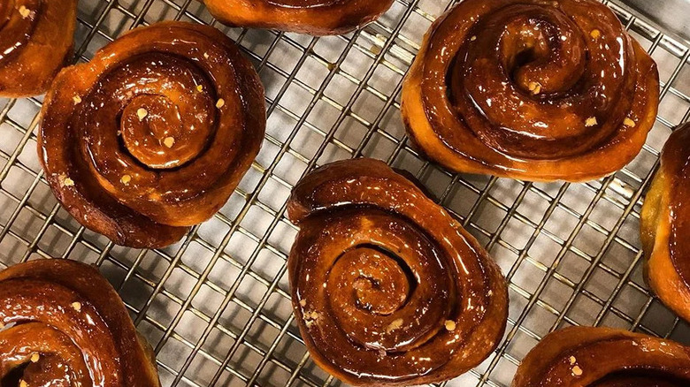 Close-up shot of a batch of glazed sweet rolls laid out on a cooling rack