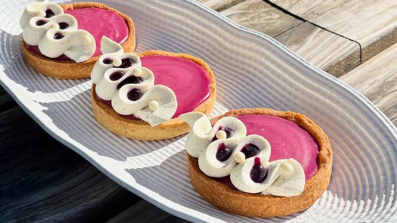 Three huckleberry tarts arranged on a long serving plate