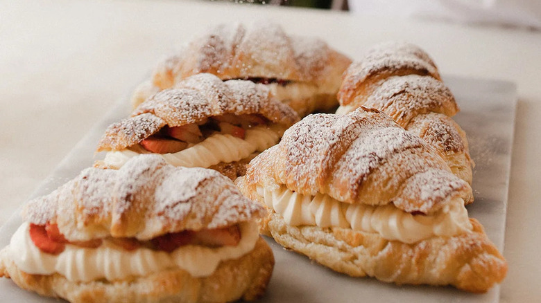 A marble slab topped with four fresh-fruit turnovers dusted with powdered sugar