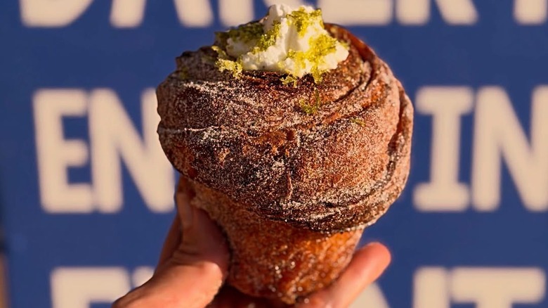 Hand holding out a key lime pie cruffin