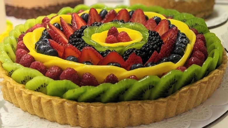 A photo of Pastiche's fresh fruit tart, consisting of neat rows of alternating fruits (kiwi, raspberries, pineapple, blueberries etc.) covered in glaze and baked in tart crust