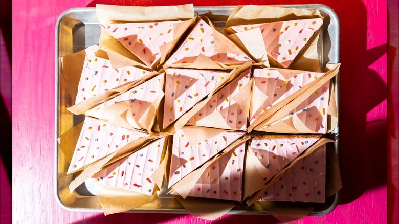 Tray of Comadre's signature pink-frosted sheet cake cut into slices