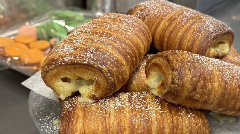 A plate full of croissants filled with banana and vanilla custard and topped with powdered sugar