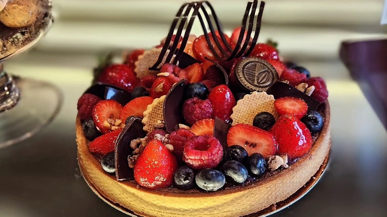 A full, signature Atelier Ortega chocolate tart with berries on display in the bakery's case