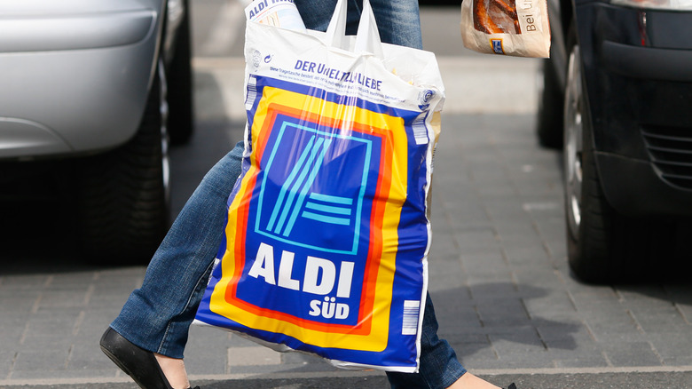 Person carrying an Aldi grocery bag in the street