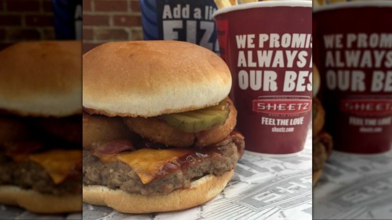 A Sheetz burger next to a cup of fries and a drink.