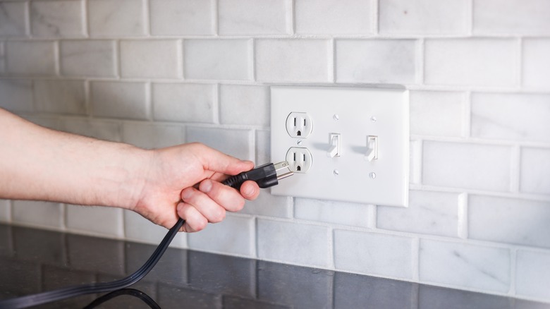 Person plugging a cord into a wall