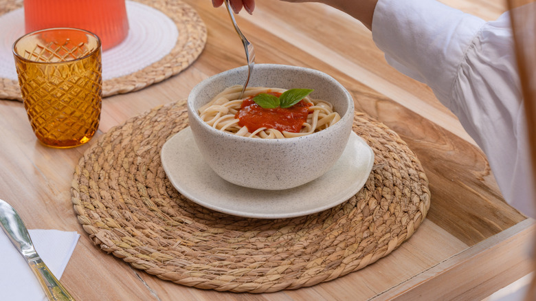 A bowl of pasta on a wicker straw rattan placemat
