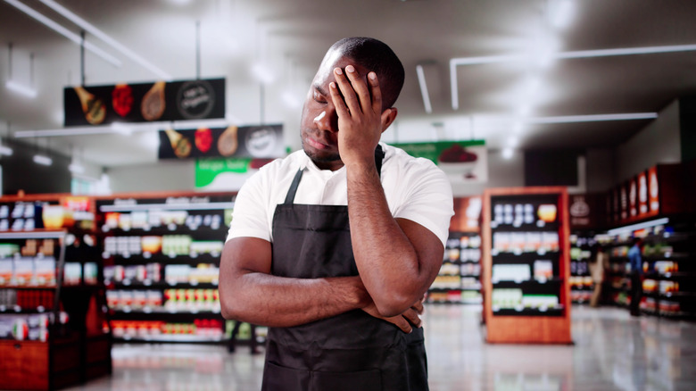 A grocery store employee looking dissapointed